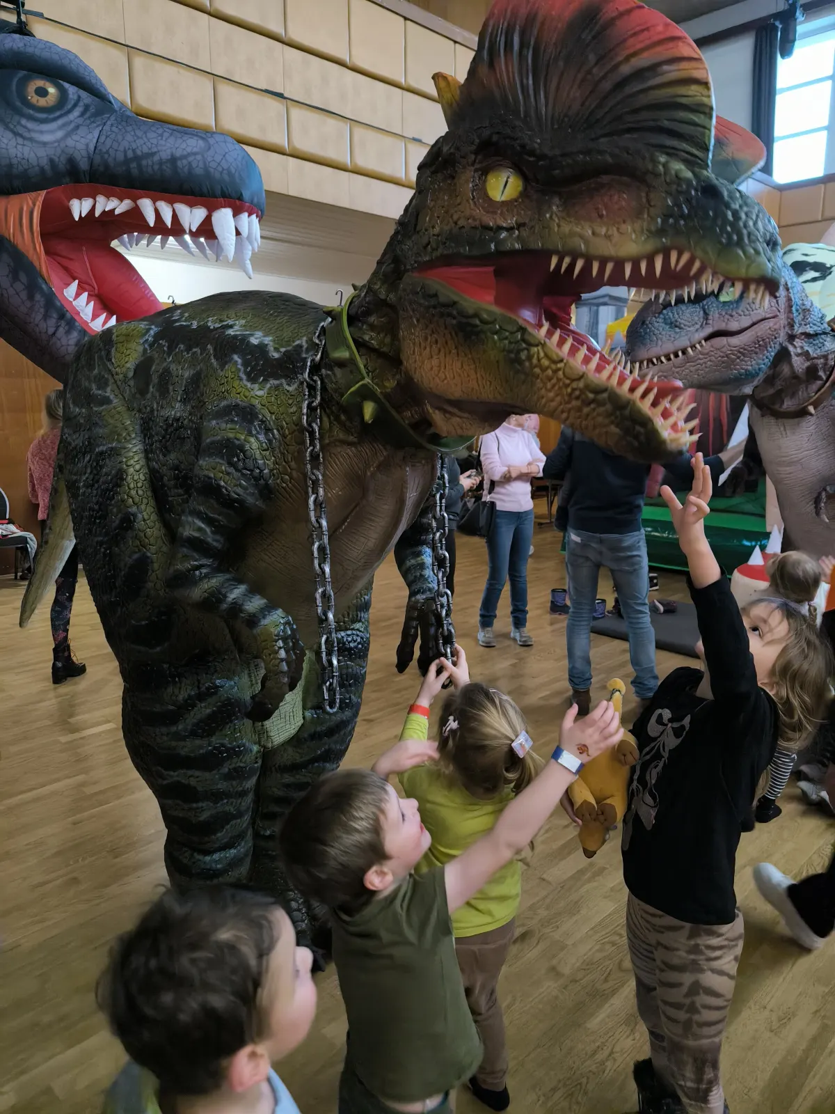 Děti nadšeně sahají na dinosauří kostým