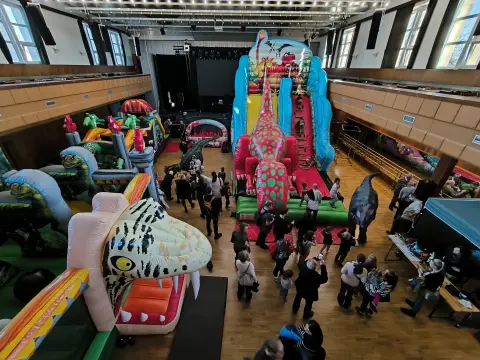 Hala plná dinosauřích skákacích hradů a atrakcí Dino show