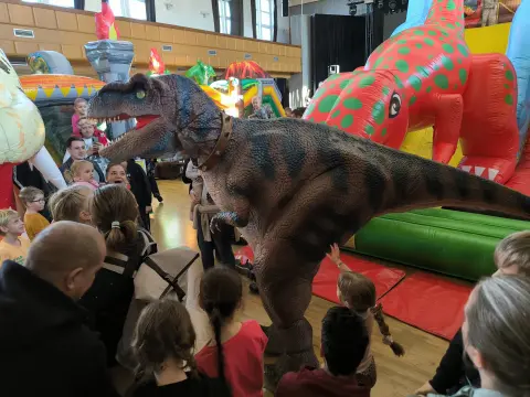 Animátor v kostýmu T-rexe prochází mezi návštěvníky